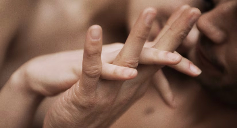 Gros plan sur les mains de deux personnes délicatement entrelacées, évoquant l'intimité et la tendresse.