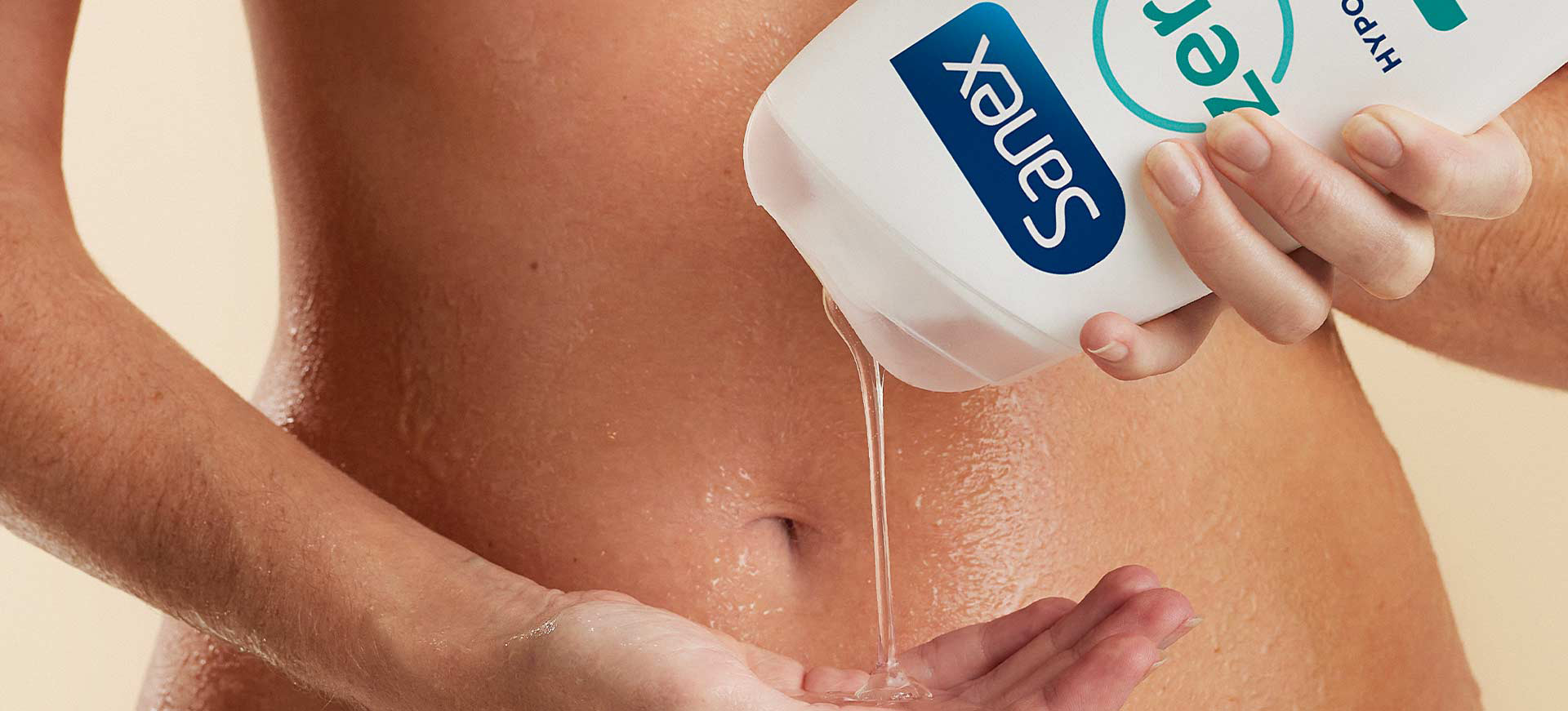 Gros plan sur le ventre d'une personne qui verse un gel douche transparent depuis un flacon Sanex Zero% dans le creux de sa main.