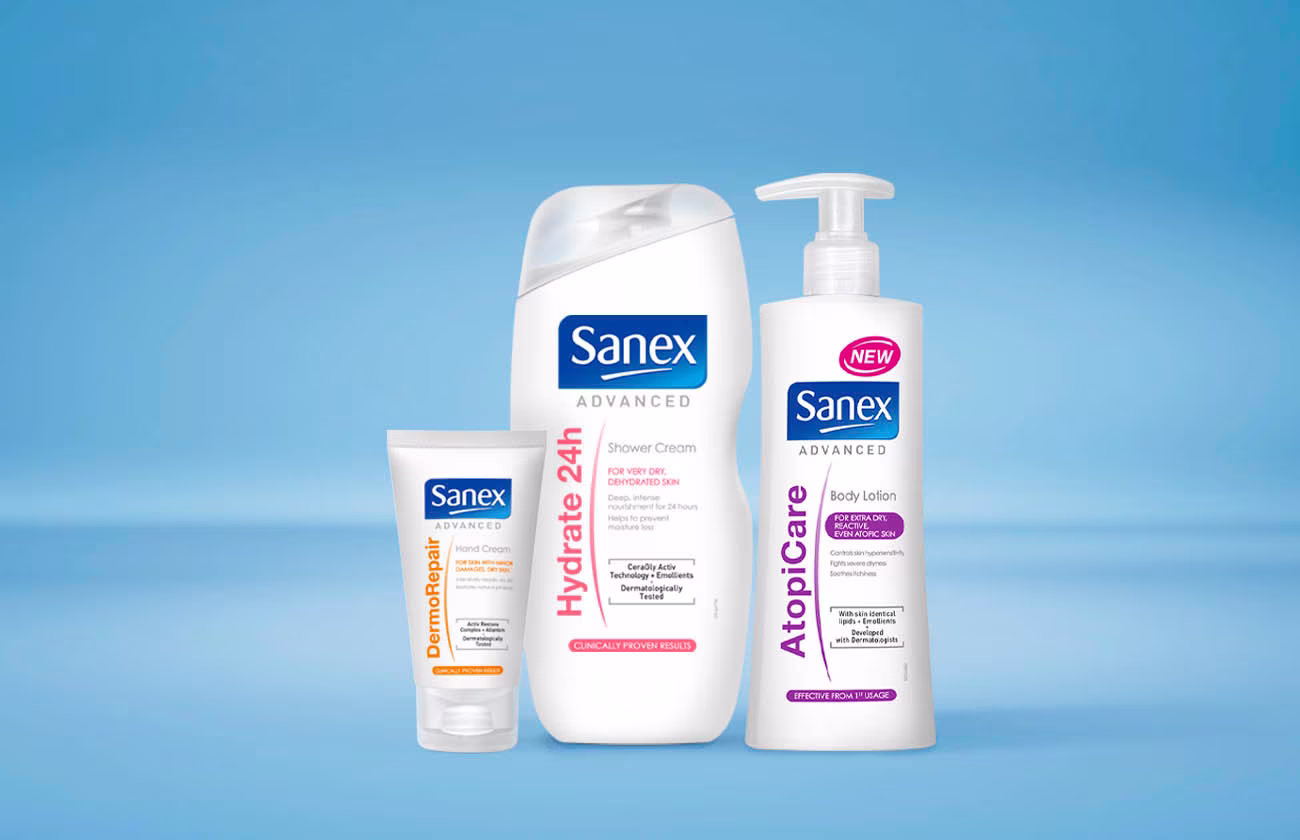 Gamme de produits Sanex Advanced, incluant une crème DermoRepair en tube, une crème de douche Hydrate 24h, et une lotion pour le corps AtopiCare.
