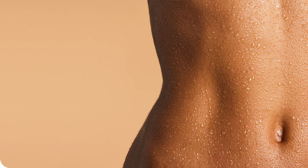 Gros plan sur l'abdomen et le flanc d'une personne à la peau tonique, couverte de fines gouttelettes d'eau.